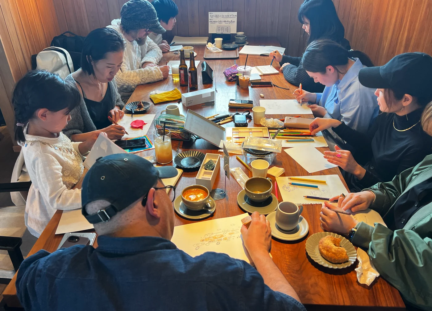 長いテーブルを囲んで絵を描く、Odd Pencilsの参加者たち。